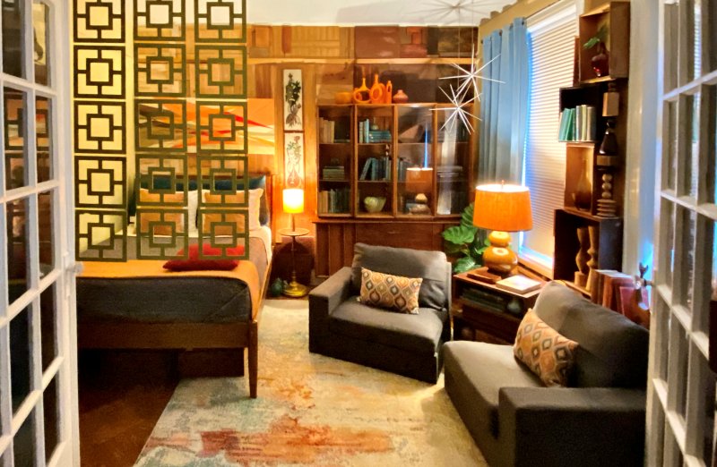 Mid-century den with a green geometric screen, a glass display bookcase, and a starburst wall accent